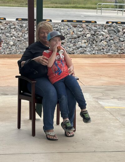 Little boy sits on a ladies lap while enjoying the party.