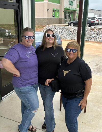 Vet staff and community members wearing cool and silly glasses smiling in front of the clinics doors.