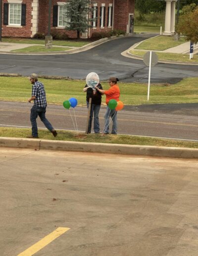 Several people by the street putting up balloons.