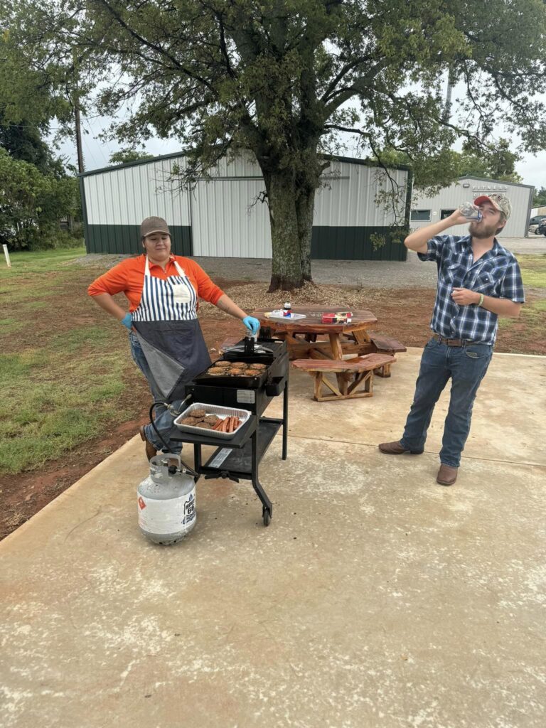 Chef grills hamburgers and hotdogs while party goers enjoy the party.