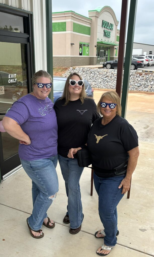Vet staff and community members wearing cool and silly glasses smiling in front of the clinics doors.
