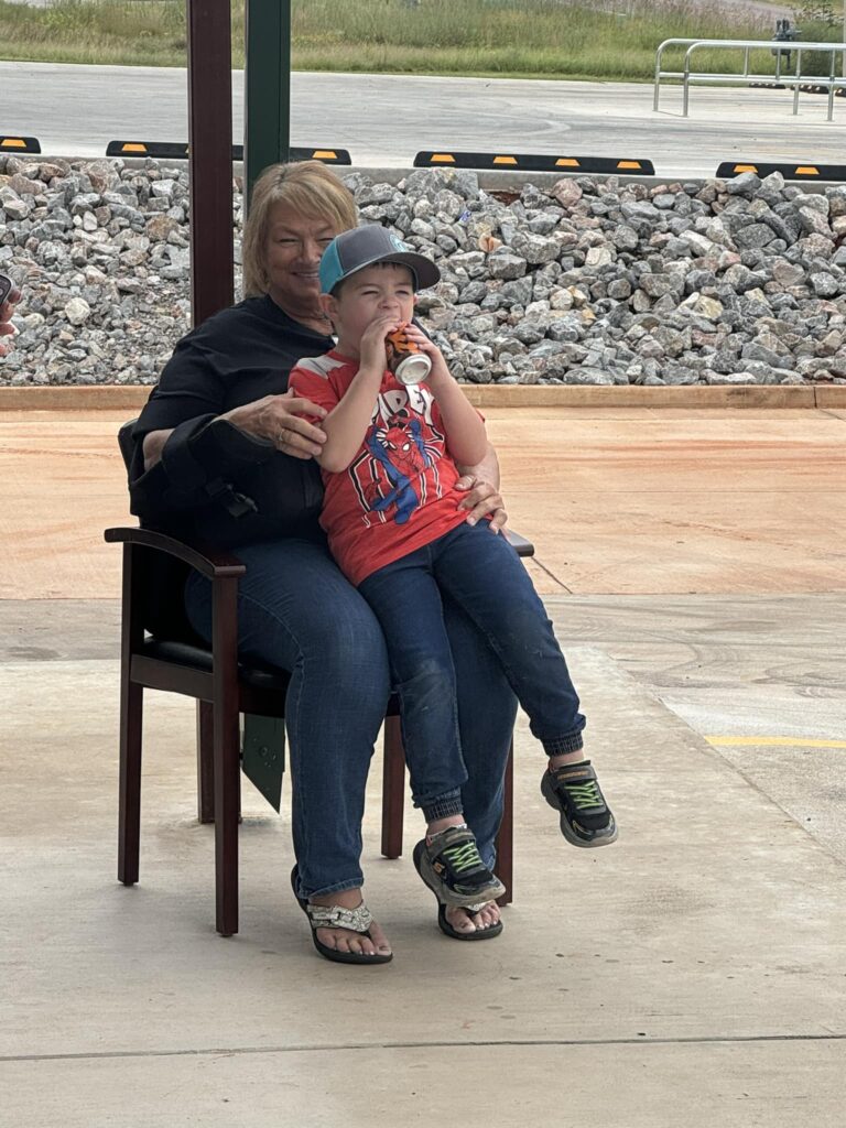 Little boy sits on a ladies lap while enjoying the party.