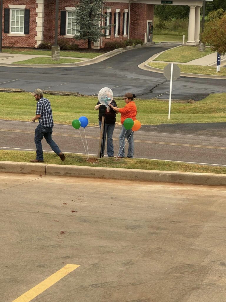 Several people by the street putting up balloons.